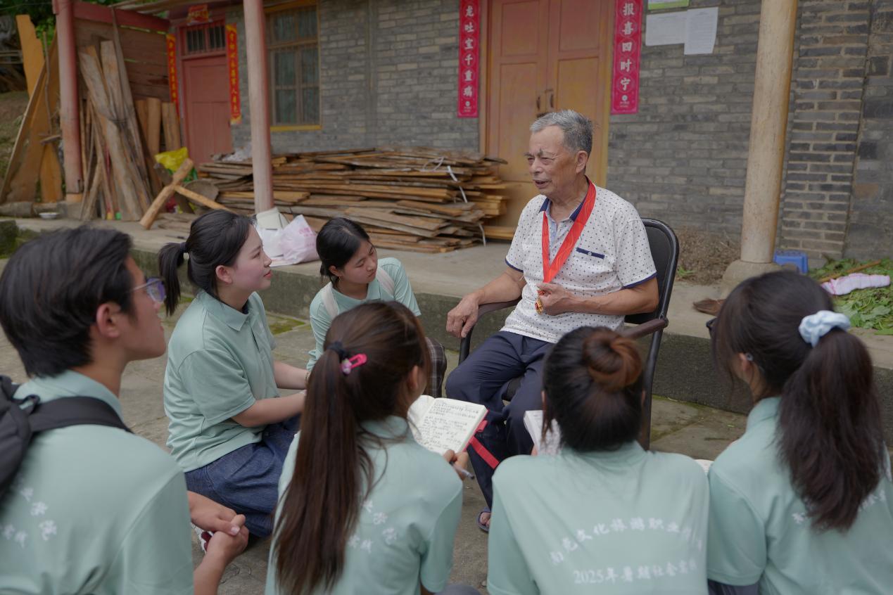 图为：实践团队听党龄50年老党员讲述身边人、身边事